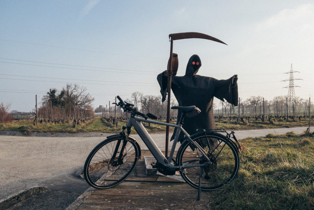 Vélo devant un épouvantail représentant la mort. Danger de rouler en vélo.